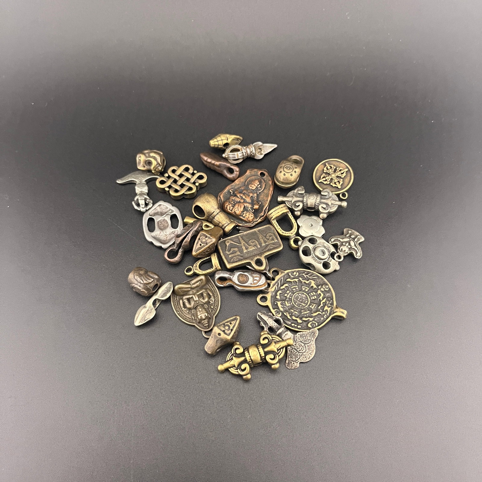 GROUP OF SMALL TIBETIAN AMULETS AND BEADS: Long: 0.5 inch to 1.38 inch; Width: 0.45 inch to 0.98 inch; High: 0.13 inch to 0.18 inch; . Wooden base for display only