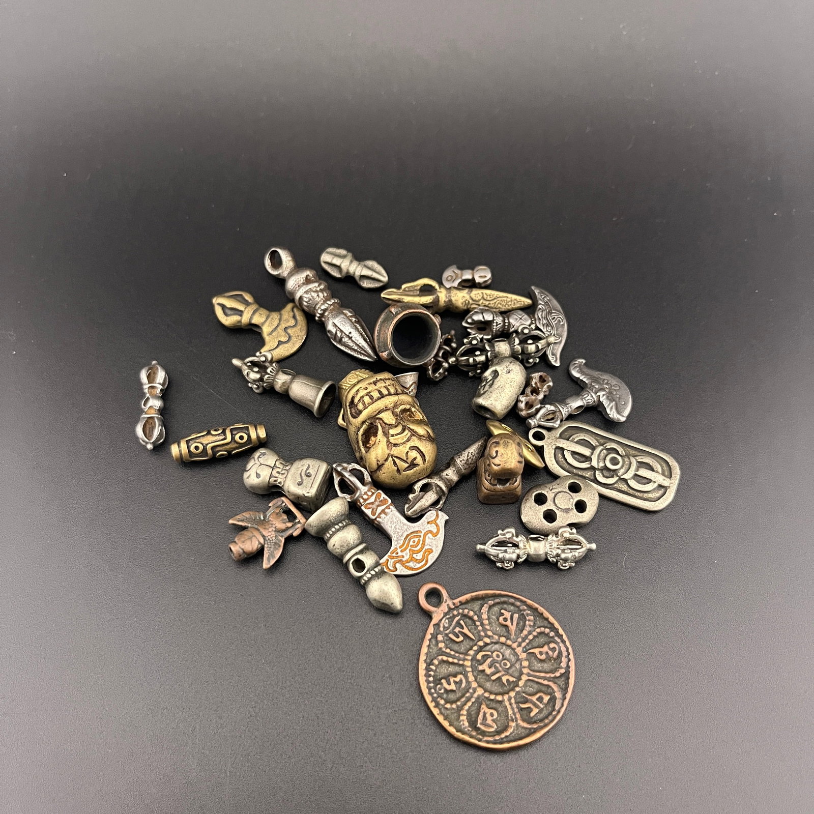 GROUP OF SMALL TIBETIAN AMULETS AND BEADS: Long: 0.46 inch to 1.4 inch; Width: 0.3 inch to 1.18 inch; High: 0.1 inch to 0.12 inch . Wooden base for display only