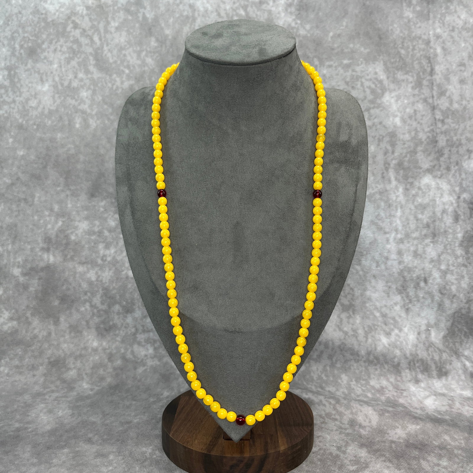 A FINE BEESWAX AMBER MADE NECKLACE: Modern; Long: 13.5 inch; Diameter: 0.22 inch.. Wooden base for display only