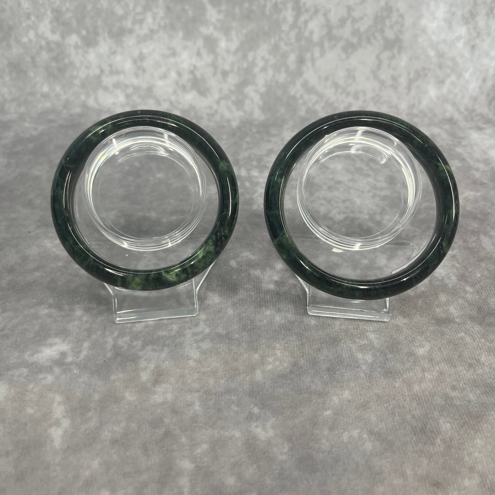 PAIR OF DARK GREEN NEPHRITE JADE BANGLE: Modern; Diameter: 2.45 inch; Diameter: 2.19 inch; . Wooden base for display only