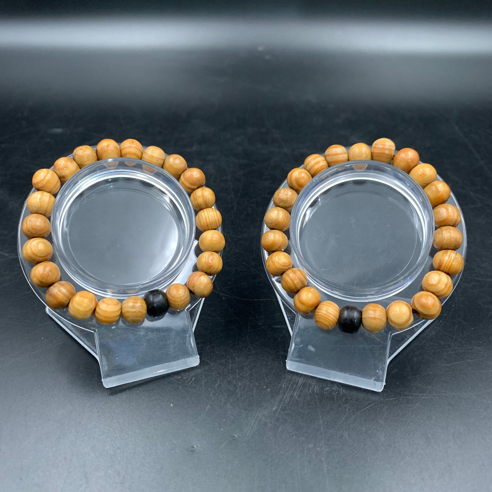 PAIR OF CEDAR WOOD BEAD BRACELETS: Modern; Long: 3.6 inch; Diameter: 0.3 inch; . Wooden base for display only