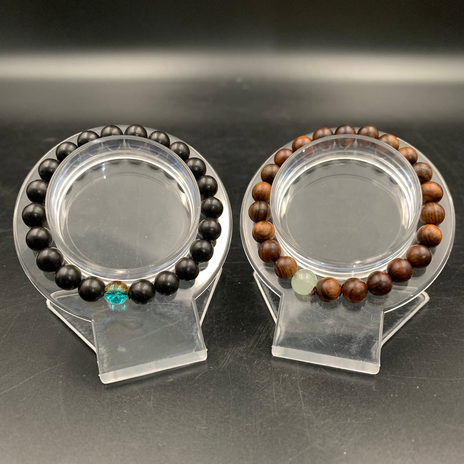 PAIR OF CEDAR WOOD BEAD BRACELETS: Modern; Long: 2.6 inch; Diameter: 0.3 inch; Long: 3.5 inch; Diameter: 0.3 inch; . Wooden base for display only