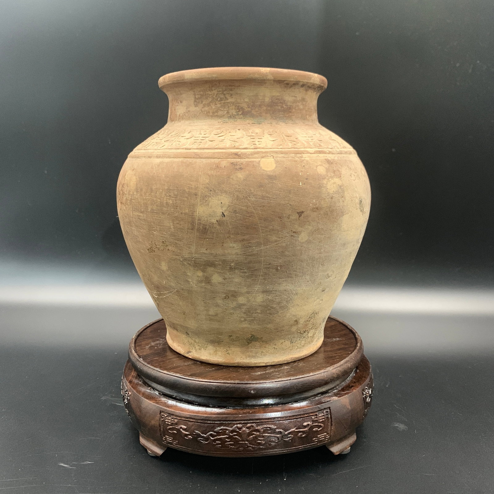 ARCHAIC HAN-STYLE UNFIRED EARTHENWARE JAR: Tang Dynasty Style; High: 6.6 inch; Diameter: 6.4 inch; . Wooden base for display only