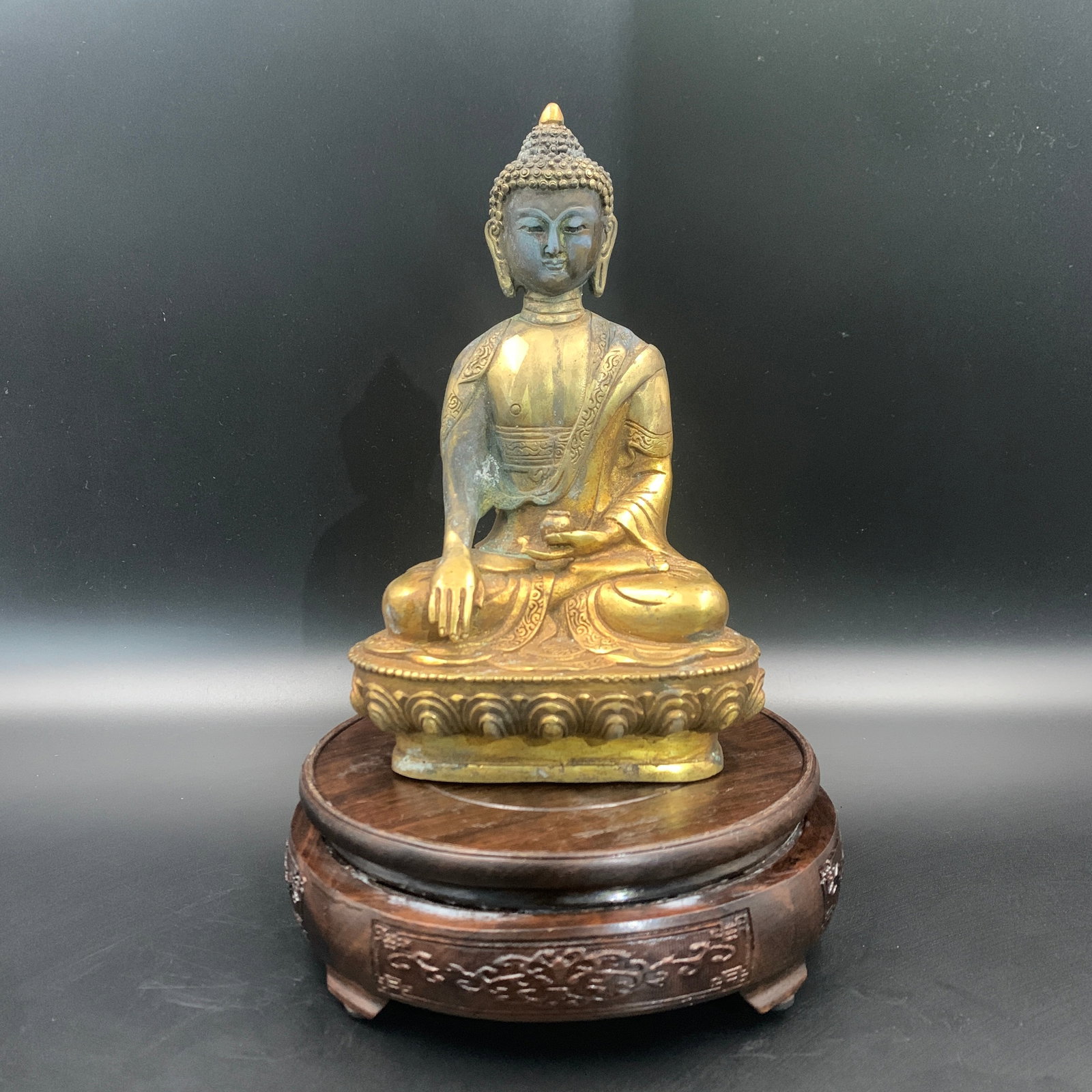 GILT-BRONZE SEATED SHAKYAMUNI BUDDHA: Qing Dynasty; Long: 4.8 inch; Width: 3.2 inch; High: 7.9 inch; . Wooden base for display only