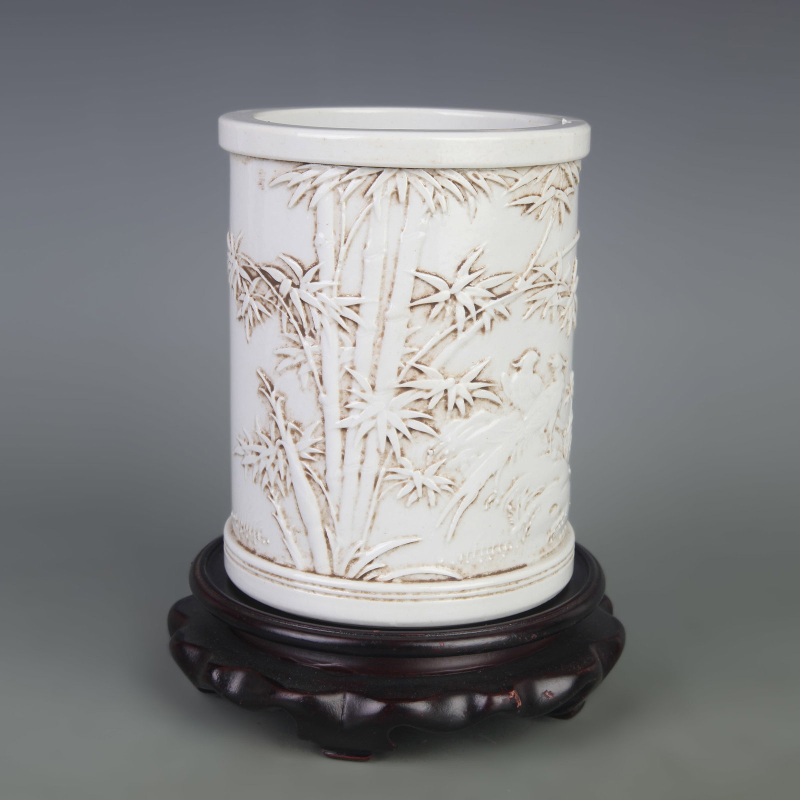 A WHITE PORCELAIN BRUSH POT CARVED WITH FLORAL AND BIRD MOTIFS
