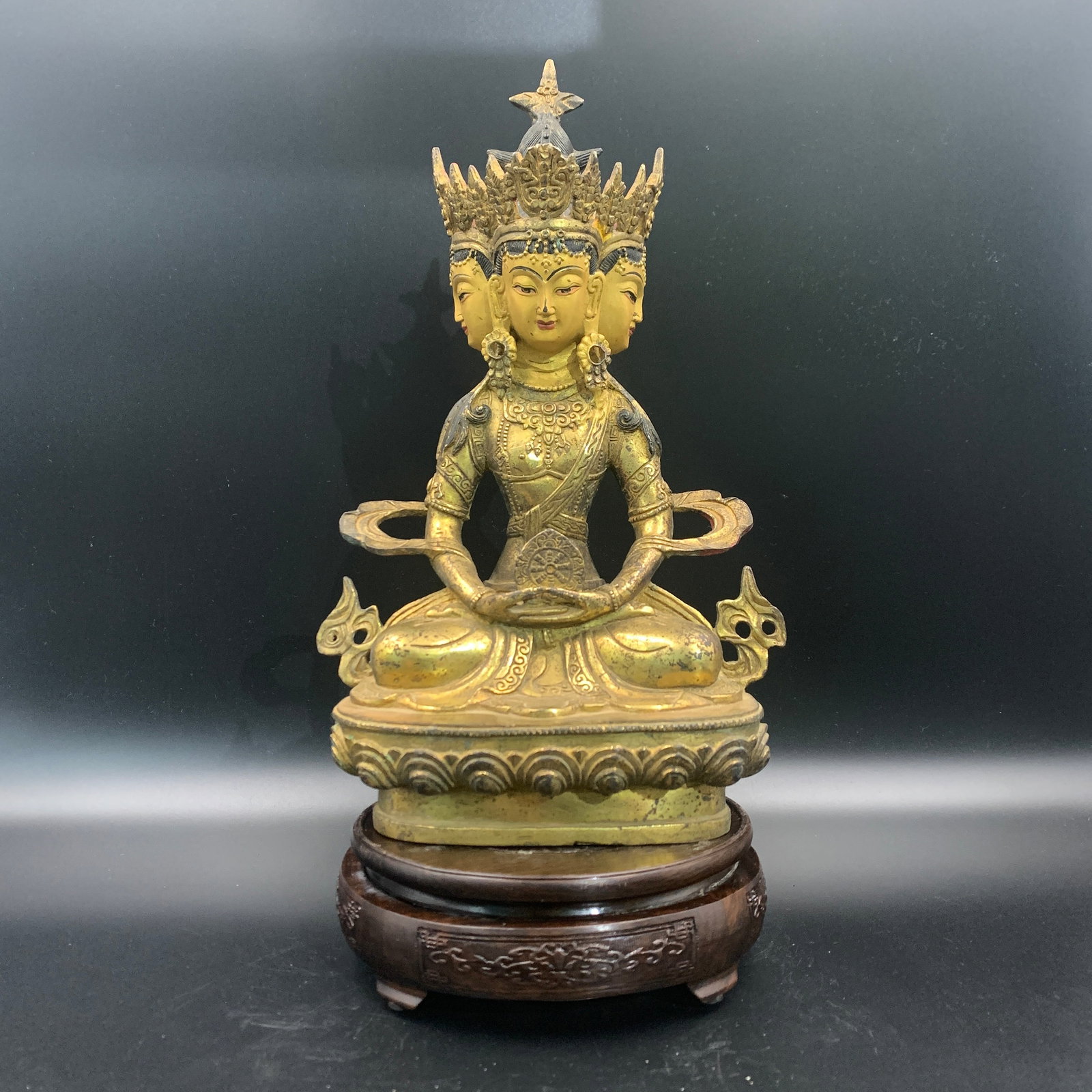 GILT-BRONZE THREE-HEADED SEATED BODHISATTVA ON LOTUS BASE