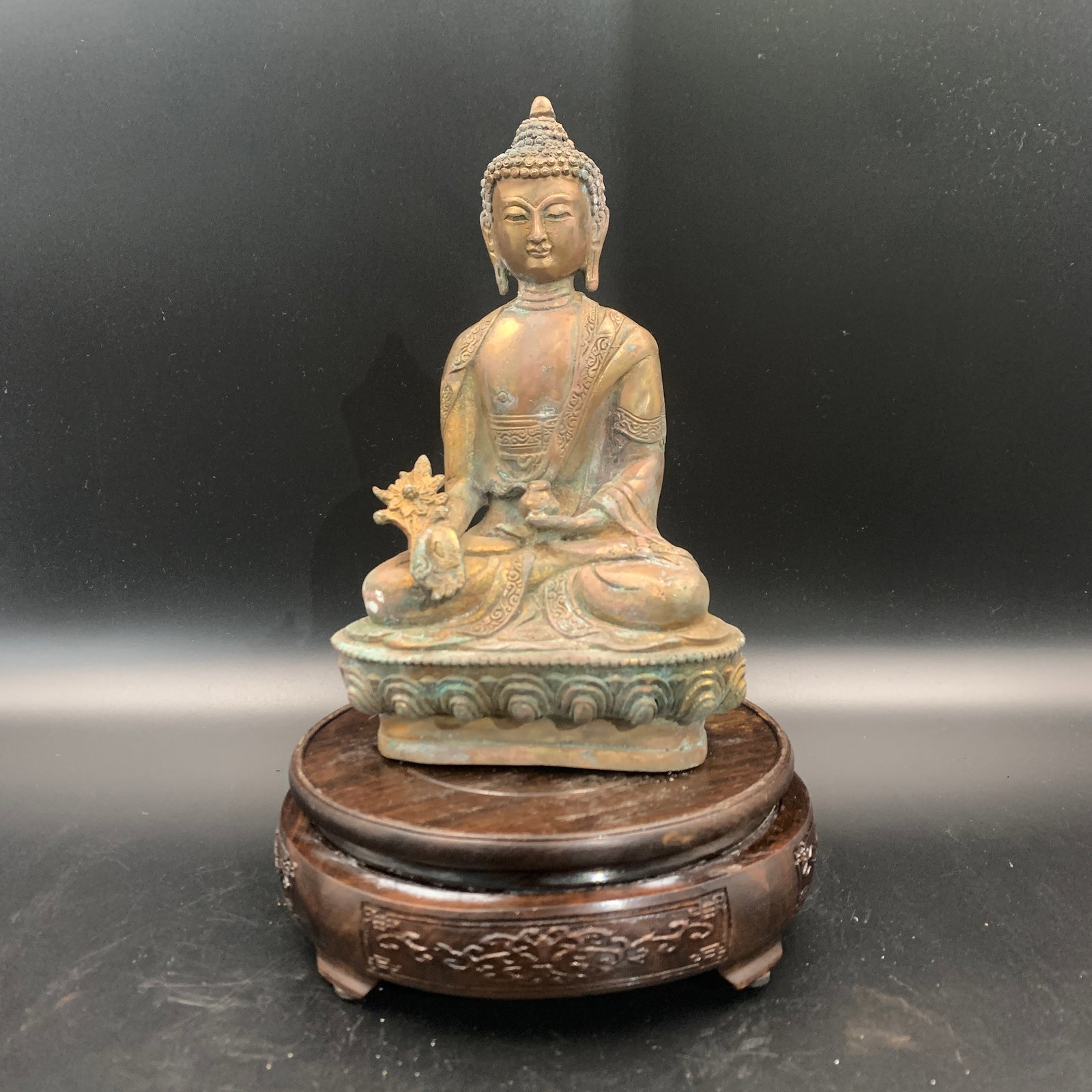 GILT-BRONZE SEATED FIGURE OF MEDICINE BUDDHA ON A LOTUS: Qing Dynasty; Long: 5 inch; Width: 3.4 inch; High: 7.9 inch; Wooden base for diplay only