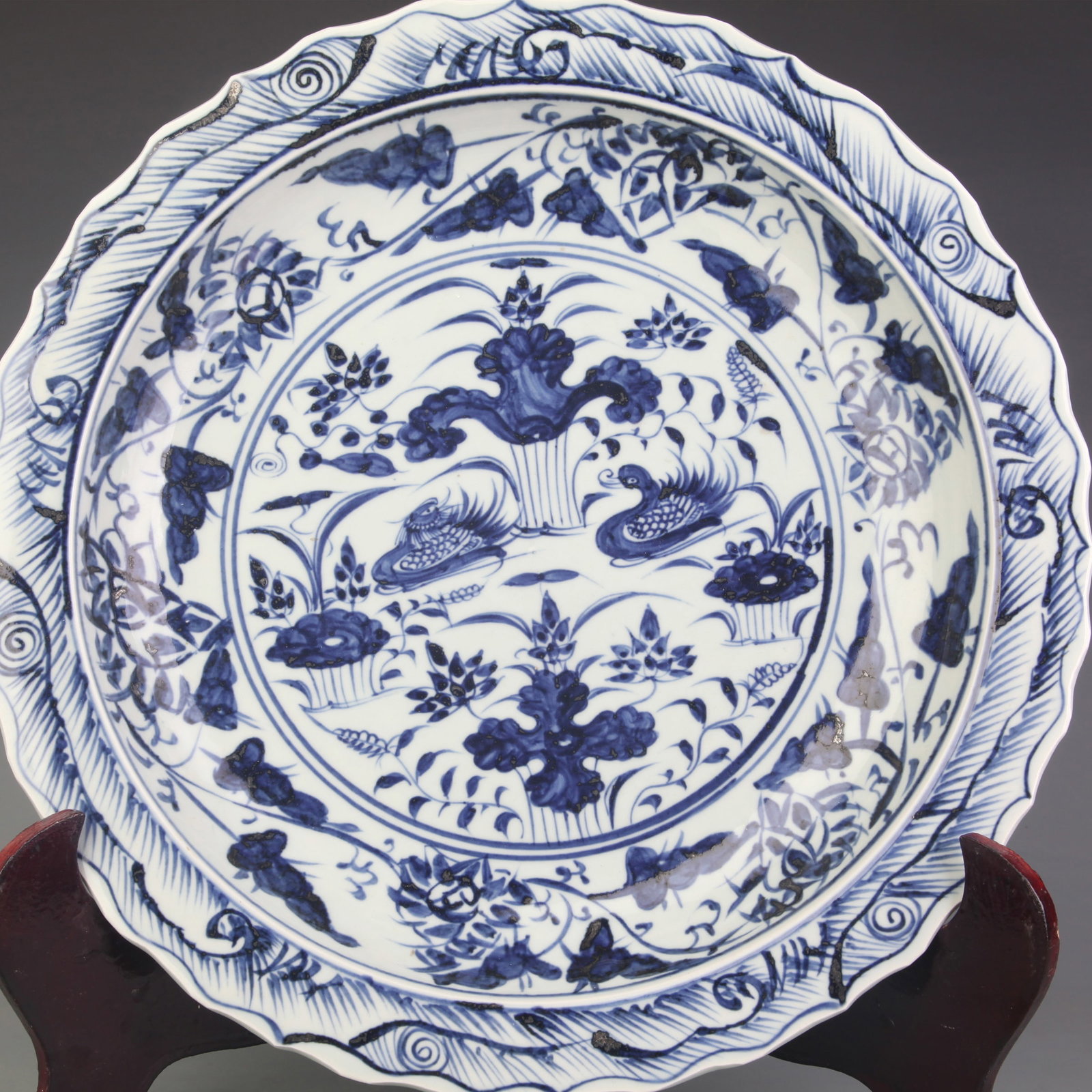 LARGE BLUE AND WHITE FOLIATE-RIM DISH WITH FLORAL DECORATION: Qing Dynasty; Diameter:15.9 inch; High: 2.5 inch; Wooden base for diplay only