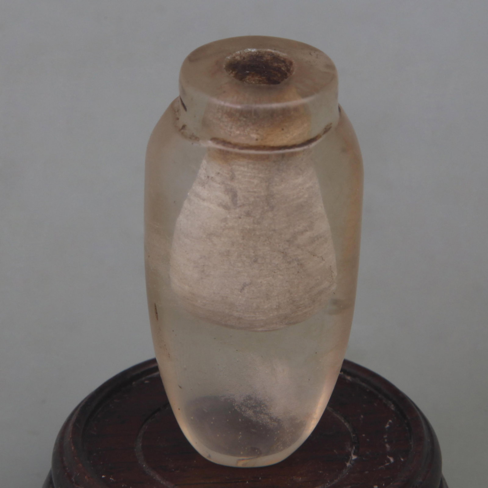 A FINE CRYSTAL GLASS SNUFF BOTTLE: Qing Dynasty; High: 2.3 inch; Width: 1.1 inch; Diameter: 0.7 inch; Wooden base for diplay only