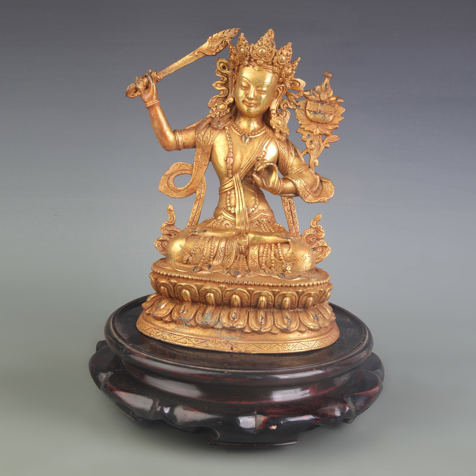 A GILDED BRONZE FIGURE OF MANJUSHRI BODHISATTVA: Qing Dynasty; Width: 7.5 inch; High: 10.0 inch; Wooden base for diplay only