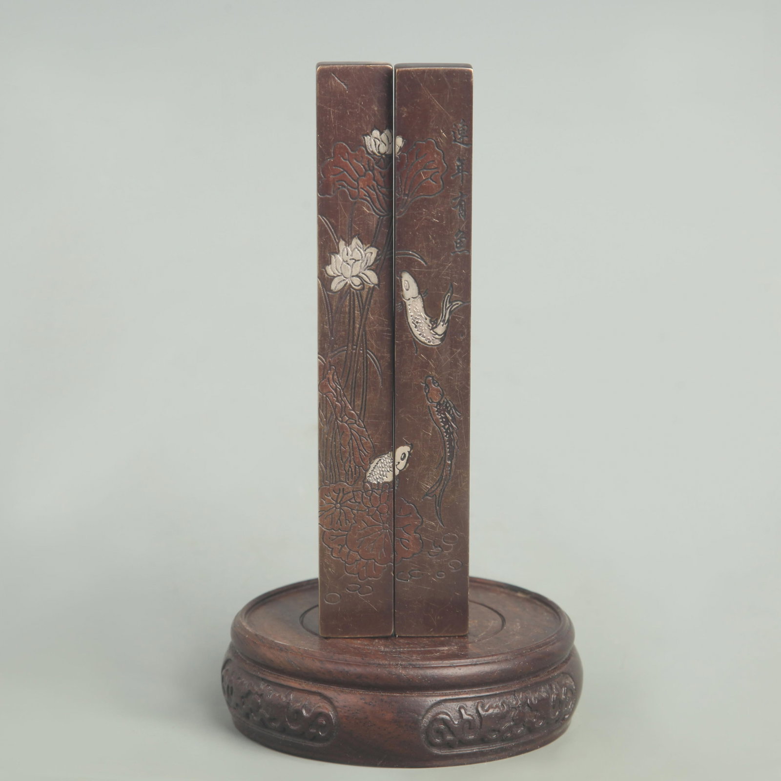BRONZE PAPER WEIGHT INLAID WITH SILVER LOTUS AND FISH PATTERN: Republic Period; High: 6.00 inch; Width: 0.75 inch; Wooden base for diplay only