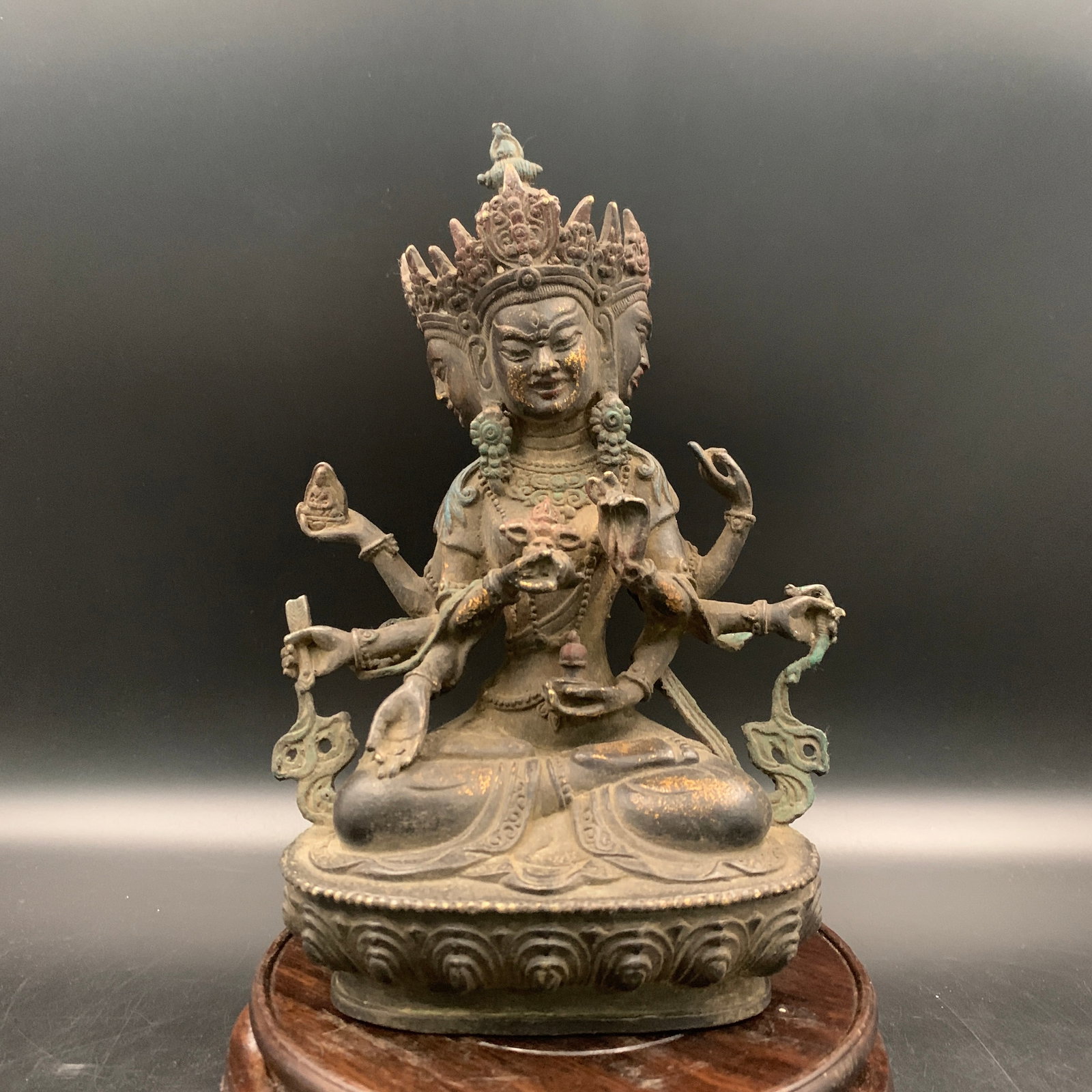 A TIBETAN GILT BRONZE FIGURE OF A THREE-HEADED, MULTI-ARMED DIORAMA DEITY