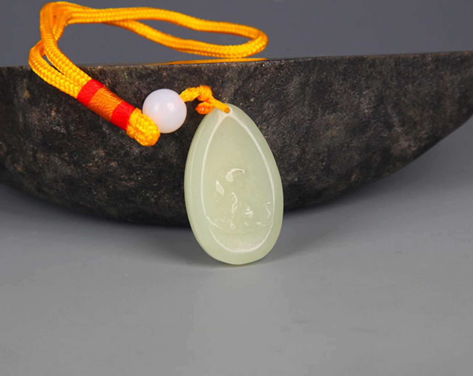 A FINELY CARVED HETIAN PALE CELADON JADE PENDANT PENDANT: Modern; High: 1.5 inch; Width: 1.0 inch; . Wooden base for display only