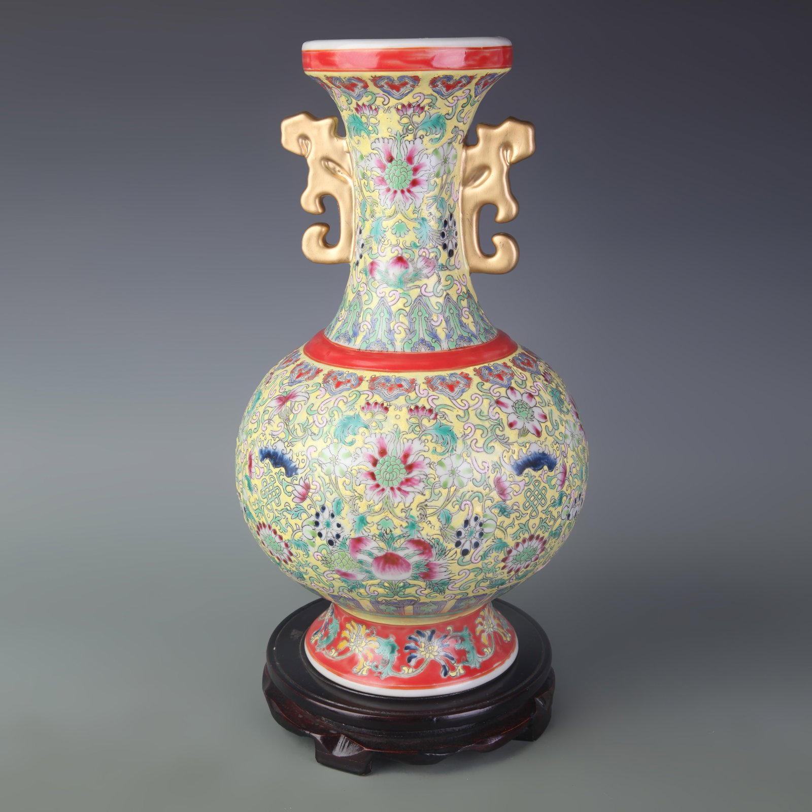 FAMILLE ROSE YELLOW-GROUND FLORAL PATTERNED TWIN-EAR PORCELAIN VASE: Qing Dynasty; Diameter: 4.4 inch; High: 13.9 inch; wooden base for picture and display purpose only.