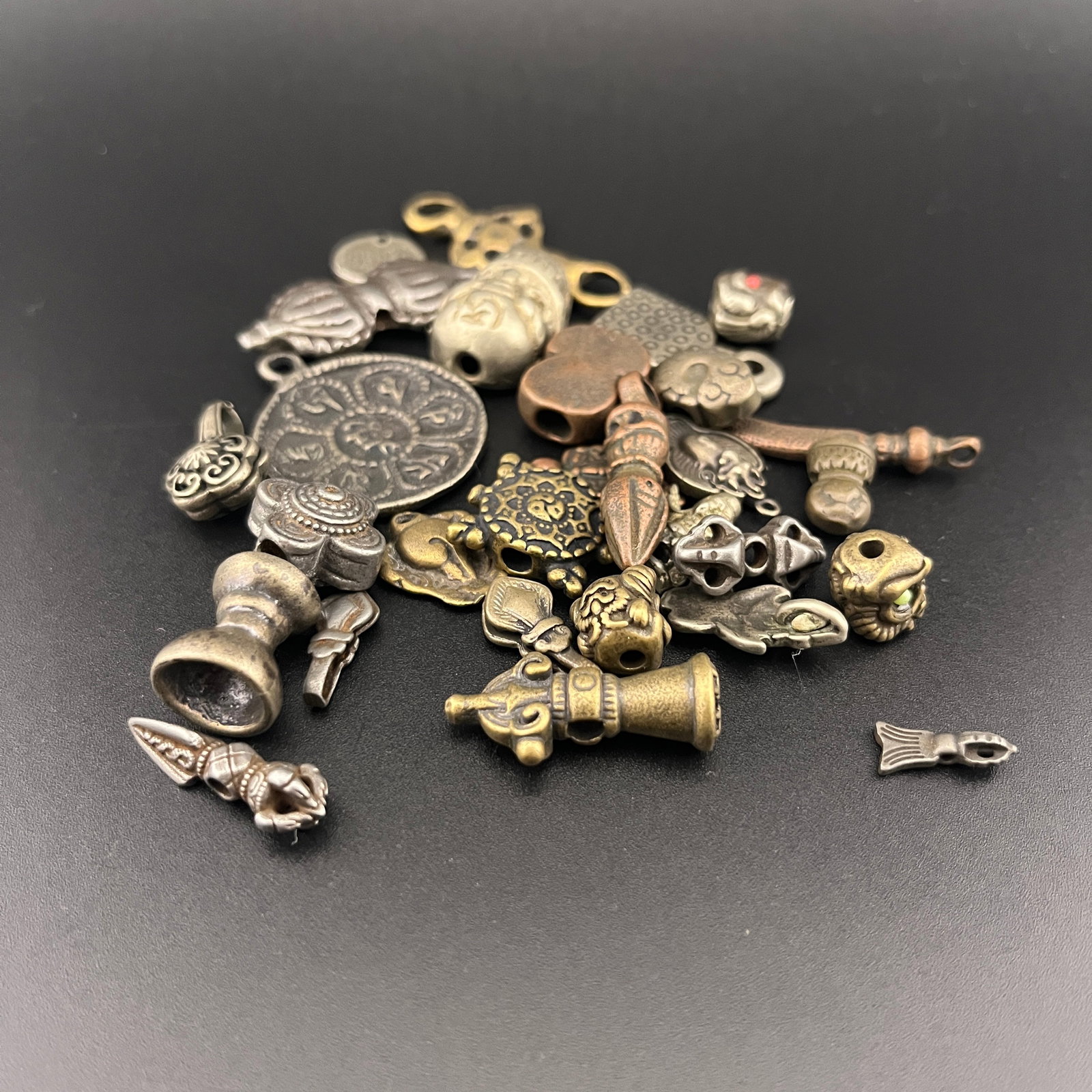 GROUP OF MINIATURE TIBETAN BRONZE THOGCHAG AMULETS: Modern; Long: 0.54 inch to 1.4 inch; Width: 0.2 inch to 1.2 inch; High: 0.1 inch to 0.16 inch;