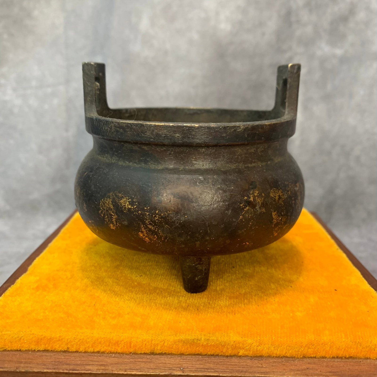 THREE-LEGGED BRONZE CENSER WITH UPRIGHT HANDLES: 20th Century; High: 3.5 inch; Diameter: 4.0 inch; wooden base for picture and display purpose only.