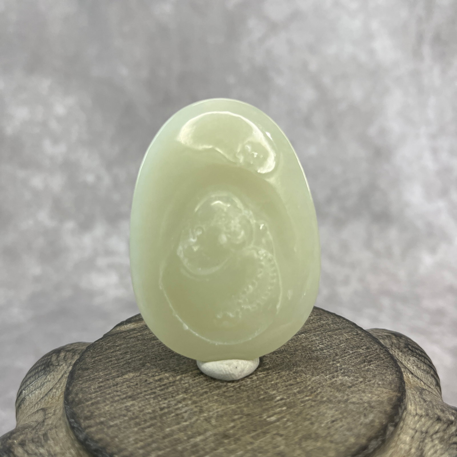 A FINE HETIAN JADE PENDANT CARVING OF A BUDAI: Qing Dynasty; Long: 2.2 inch; Width: 1.6 inch; High: 0.37 inch; wooden base for picture and display purpose only.