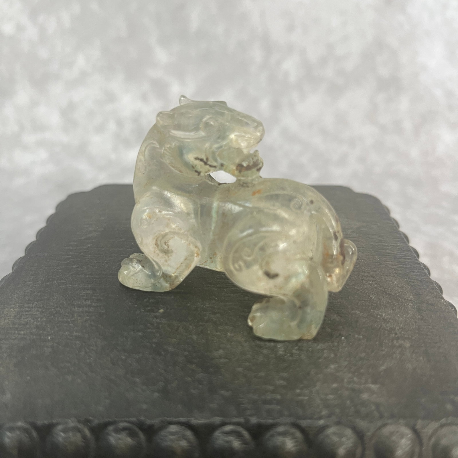 A CHINESE CARVED ROCK CRYSTAL OR PALE JADE FIGURE OF A BIXIE OR MYTHICAL BEAST: Modern; Long: 2 inch; Width:1.6 inch; High: 1.14 inch; wooden base for picture and display purpose only.