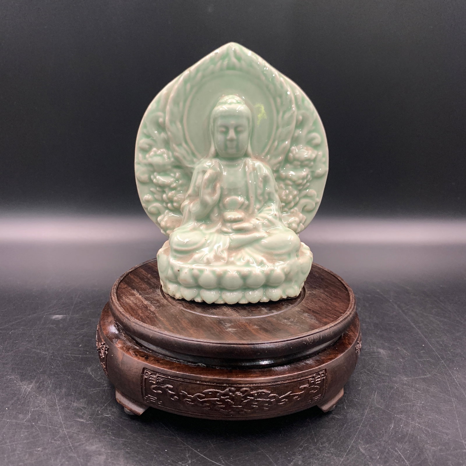 A CELADON-GLAZED MOULDED PORCELAIN FIGURE OF BUDDHA: Modern; Long: 5 inch; Width:2.6 inch; High: 5.9 inch; wooden base for picture and display purpose only.