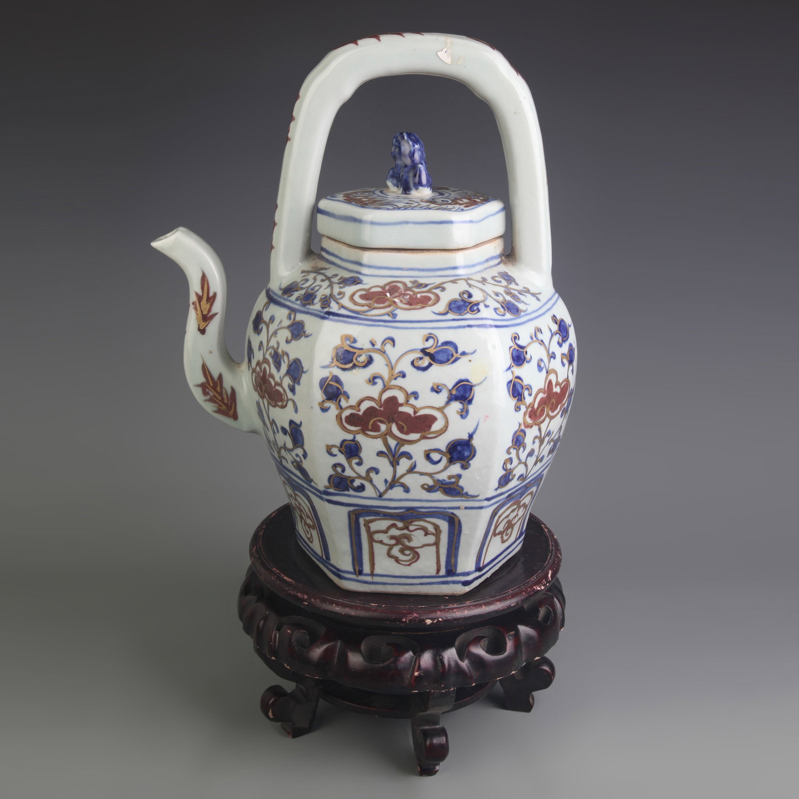 LARGE BLUE AND WHITE UNDERGLAZE-RED HEXAGONAL OVERHEAD-HANDLE TEAPOT: Ming Dynasty; Width: 10.8 inch, High: 14.0 inch; wooden base for picture and display purpose only.