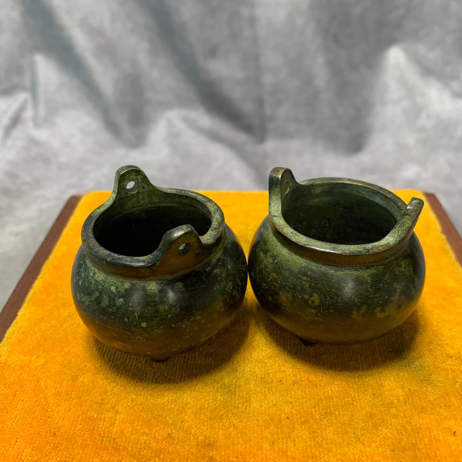 PAIR OF TWO BRONZE TRIPOD INCENSE BURNERS WITH UPRIGHT HANDLES: Ming Dynasty; High: 1.7 inch; Diameter: 1.9 inch; wooden base for picture and display purpose only.