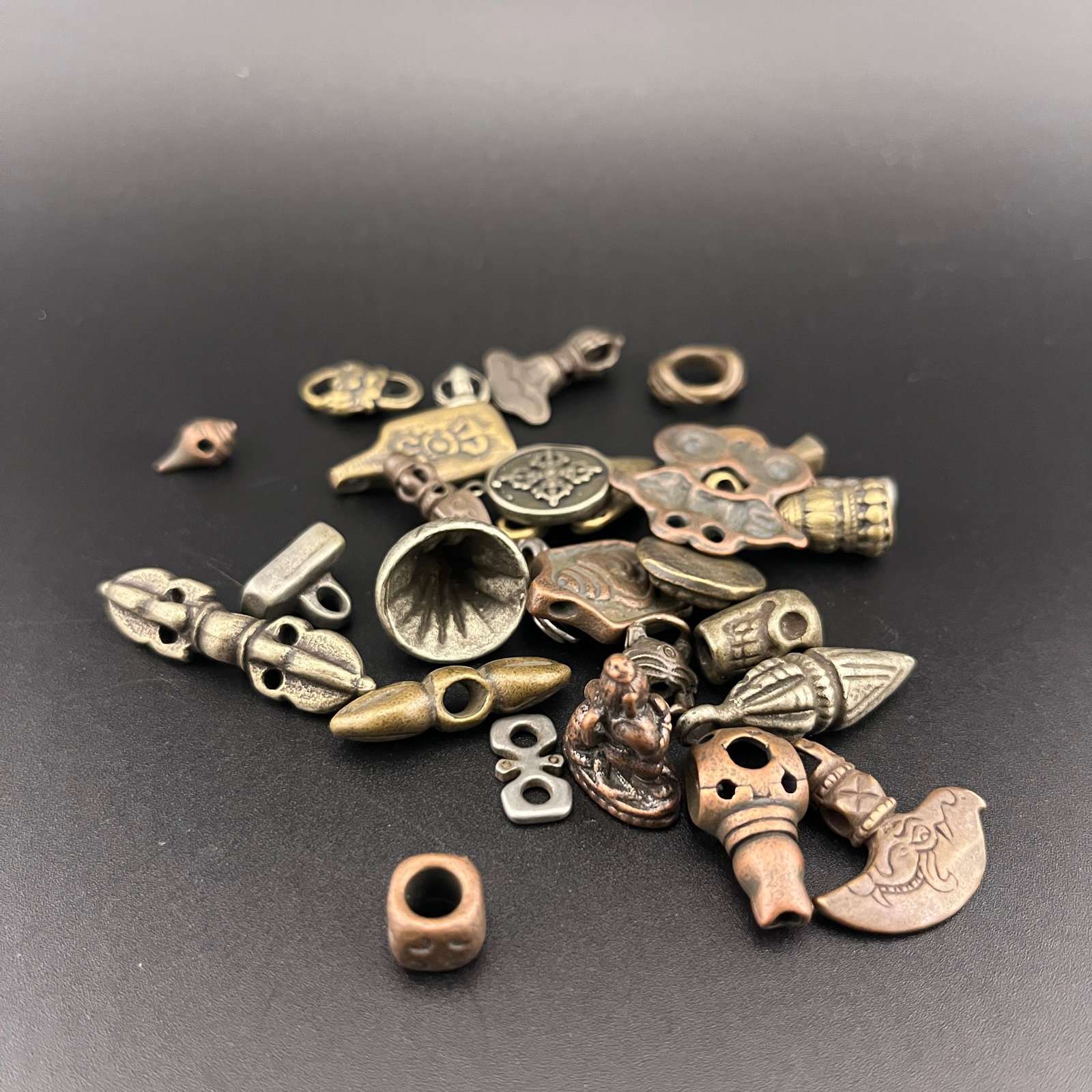 GROUP OF MINIATURE TIBETAN BRONZE THOGCHAG AMULETS: Modern; Long: 0.48 inch to 1.45 inch; Width: 0.28 inch to 0.34 inch;