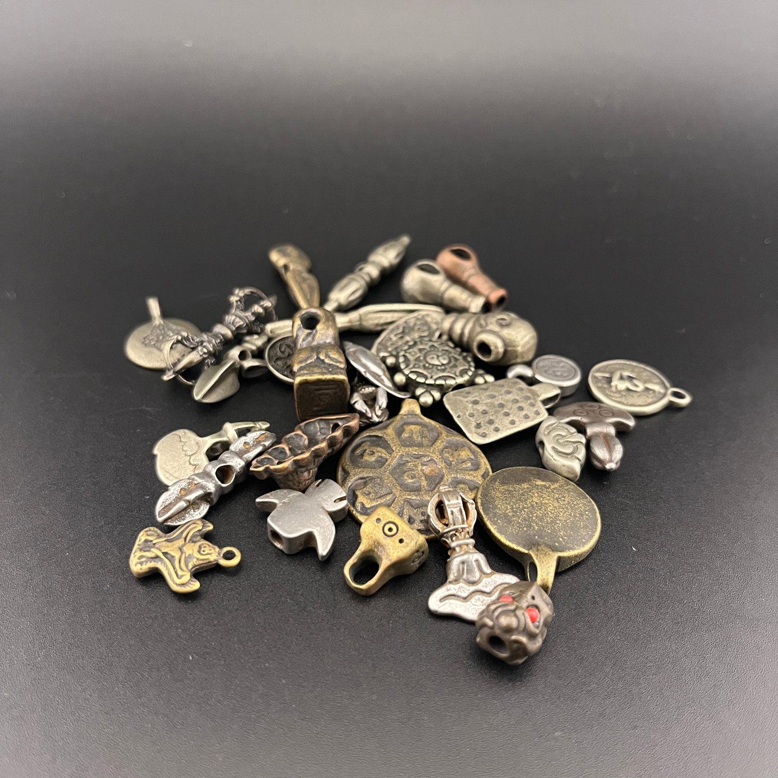 GROUP OF MINIATURE TIBETAN BRONZE THOGCHAG AMULETS: Modern; Long: 0.5 inch to 1.6 inch; Width: 0.2 inch to 0.4 inch