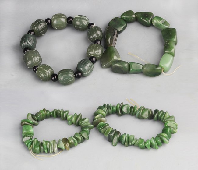 A GROUP OF FOUR CELADON JADE BRACELETS: A GROUP OF FOUR CELADON JADE BRACELETS. Contemporary, Each Bead: Diameter: 0.5 inch