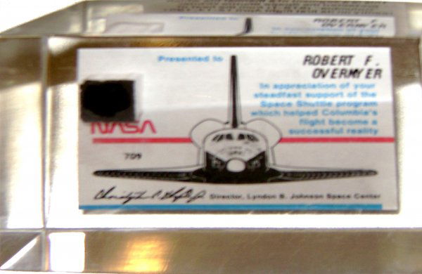 Segment of Thermal Tile Flown on STS 1: (.5 x .5") A segment of thermal tile flown on STS 1 and encased in Lucite (3.75 x 2.75 x 1") and presented to Robert F. Overmyer who was the pilot on this first Shuttle mission. Excellent condition. E