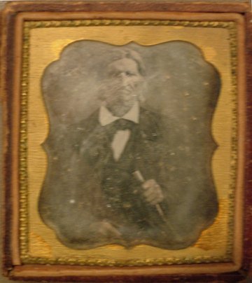 Vintage Tintype Metal Photograph in Frame: (3.5 x 2.5") Vintage metal photograph of an older man holding a walking stick (?) in a gold colored metal frame. Poor condition.