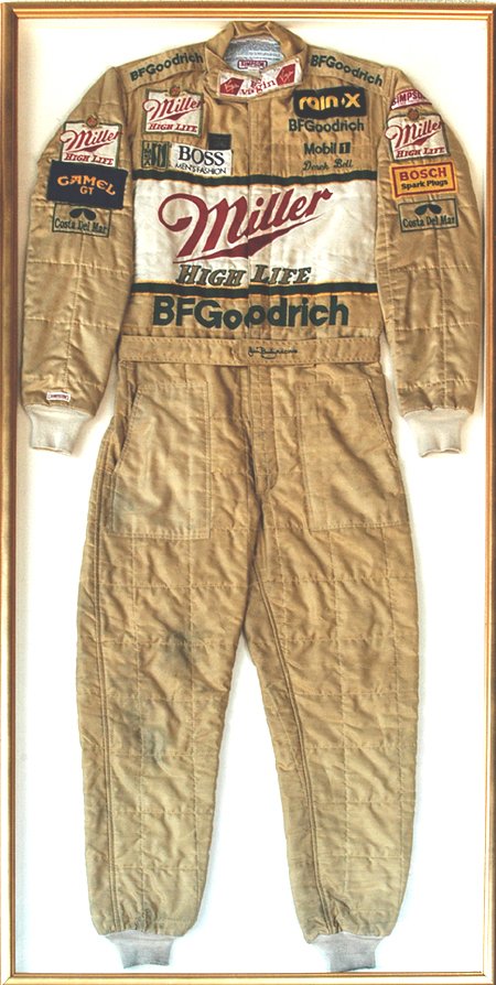 Derek Bell Racing Suit: Gold colored Miller/BF Goodrich (Jim Busby Racing) suit made by Simpson Racing Products and worn by legendary driver Derek Bell. Emblazoned with sponsors: Miller High Life, Boss, Mobile, BF Goodrich, 