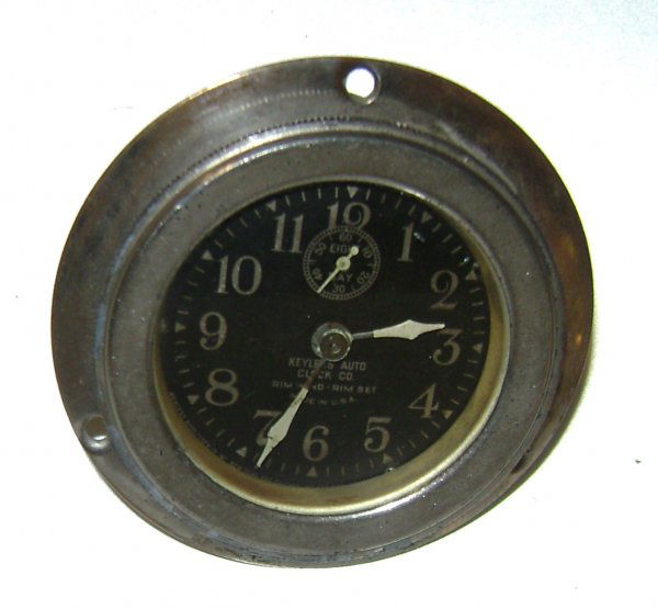Keyless Automobile Clock Co. 8 Day Rimwind Clock: This rim wind clock features a small 60 second dial beneath the 12 o'clock position and white Arabic numerals and minute, hour and second hands. Typical age wear to plating on the case.
