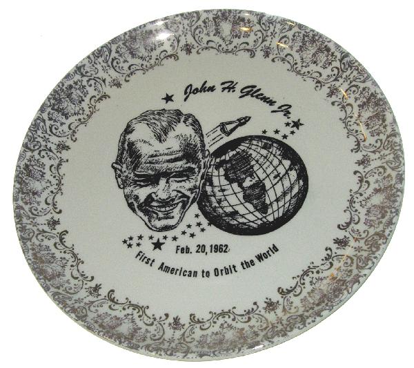 Mercury 6 John Glenn Flight Collectors Plate: (9" diameter) A ceramic collectors plate commemorating the fligtht of the Friendship 7. The cream colored plate bears a portrait of John Glenn, the globe and and the space capsule. The edge of the pla