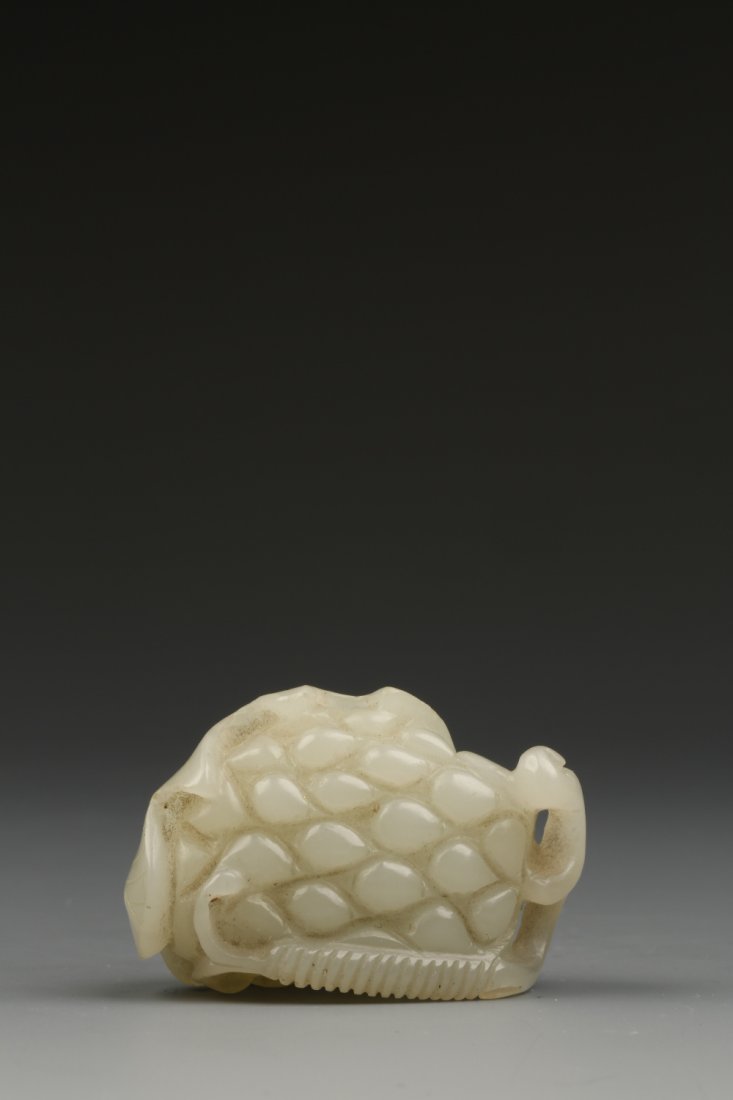A PALE CELADON JADE CARVING of a leaf partially enclosi: A PALE CELADON JADE CARVING of a leaf partially enclosing fruit, Qing, 1.75" high Provenance: The Anthony Bate Collection of Chinese Snuff Bottles and Works of Art.