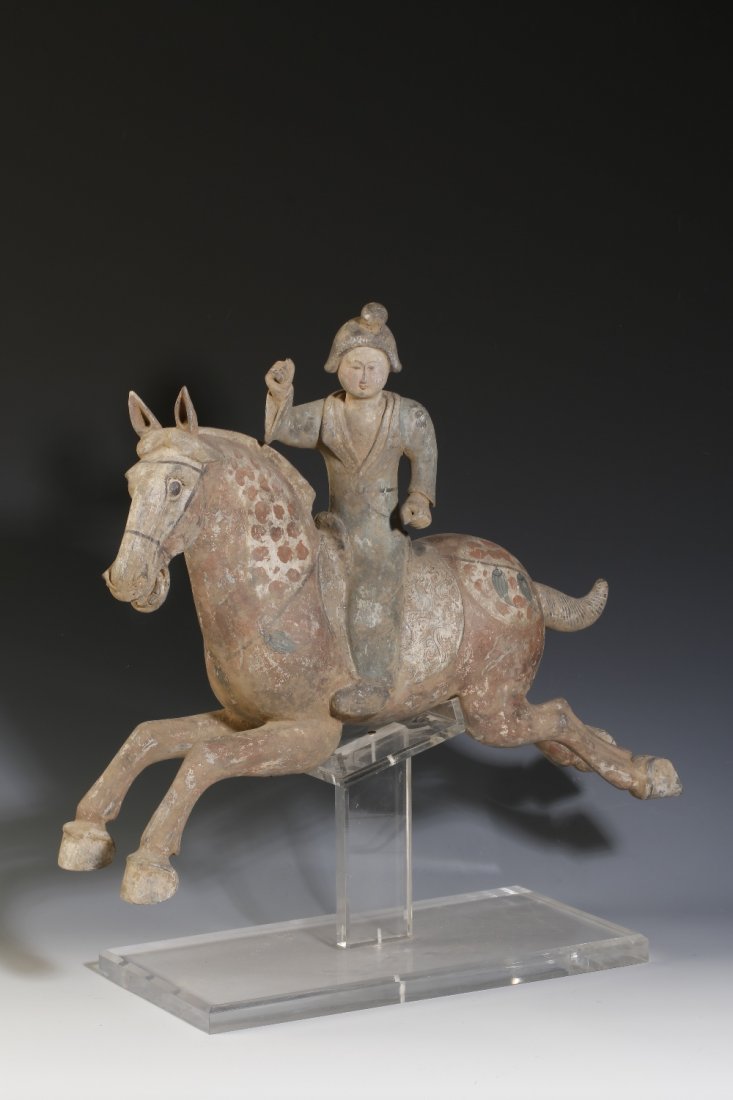 A PAINTED POTTERY FIGURE OF A HORSE AND RIDER in a gall: A PAINTED POTTERY FIGURE OF A HORSE AND RIDER in a galloping pose, probably Tang, 22" long Sold with a thermoluminescence testing certificate which is consistent with the dating of this lot.