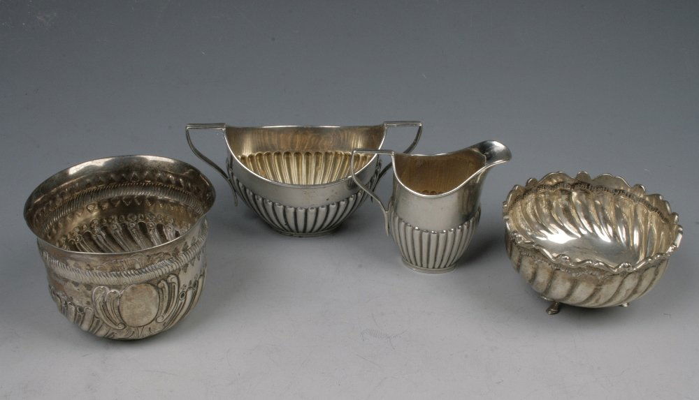 A LATE VICTORIAN MATCHING CREAM JUG AND SUGAR BOWL of o: A LATE VICTORIAN MATCHING CREAM JUG AND SUGAR BOWL of oval form with part fluted decoration, London 1897, a Victorian sugar bowl by Charles Stuart Harris, and a metalware sugar bowl (c.9.4oz) (4) ¦