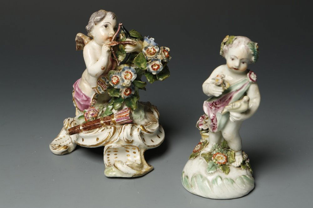 A DERBY PORCELAIN MODEL OF A PUTTO holding a bird and p: A DERBY PORCELAIN MODEL OF A PUTTO holding a bird and posy of flowers, on a floral encrusted base, the underside with three kiln pad marks, 4.75" high, and a similar Chelsea figure of Cupid (2)¦