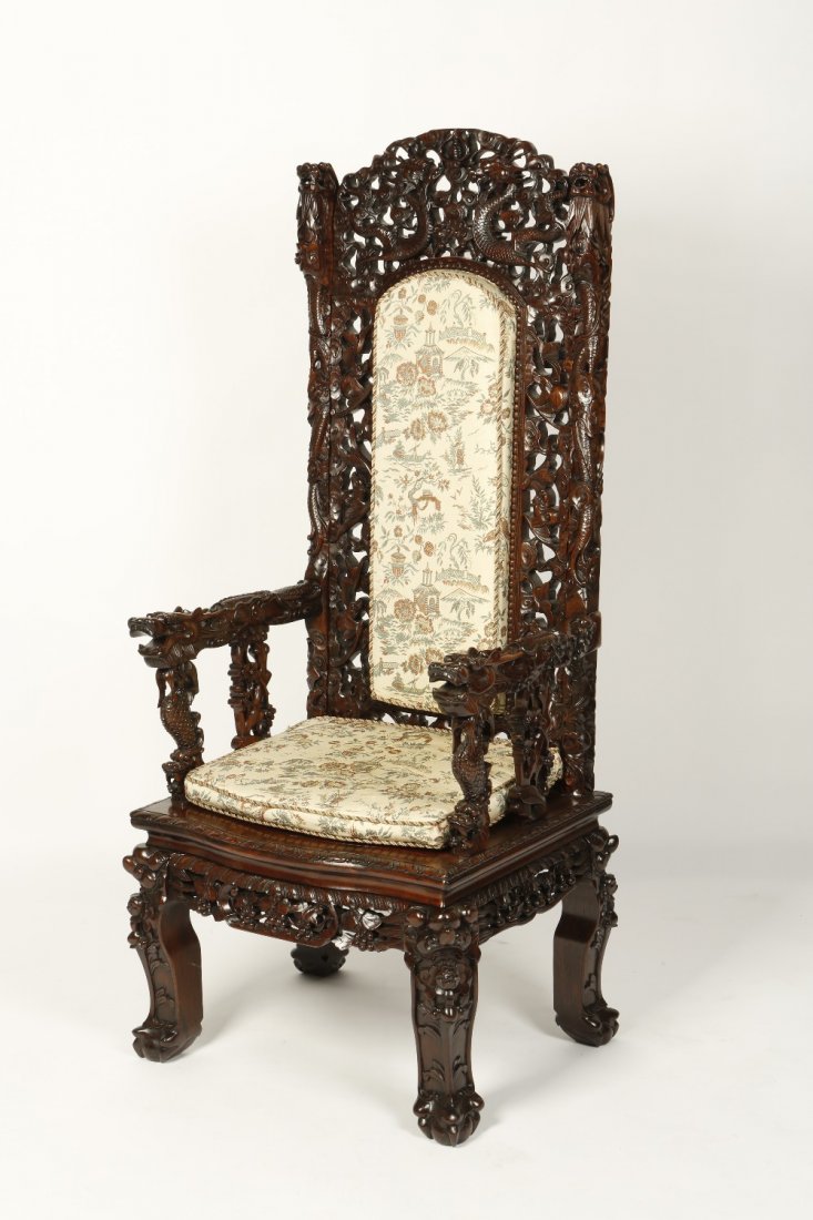 A CHINESE HARDWOOD THRONE CHAIR, the back with an uphol: A CHINESE HARDWOOD THRONE CHAIR, the back with an upholstered central section surrounded by carved dragons and bats, with conforming arms and lower area, 57" high