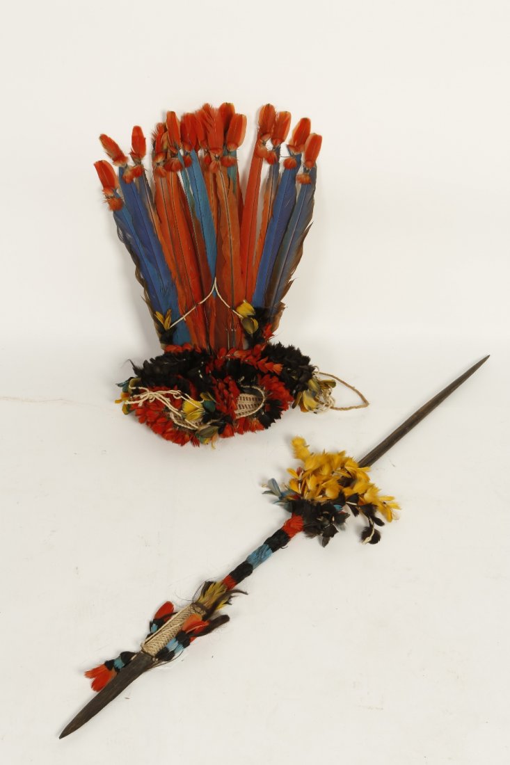 A TRIBAL SPEAR of slender pointed form, decorated with : A TRIBAL SPEAR of slender pointed form, decorated with yellow, black, red and blue feathers and woven hand hold, 41" long and a similar headdress with tall feathers and decorative headband, possibly S