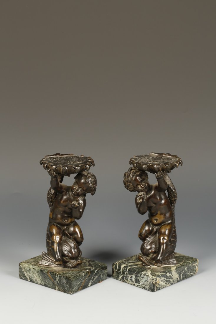 A PAIR OF RENAISSANCE STYLE CAST AND PATINATED BRONZE S: A PAIR OF RENAISSANCE STYLE CAST AND PATINATED BRONZE SCULPTURES of cherubs riding on scaly dolphins, holding seashells aloft, on marble bases, 9" high. See illustration