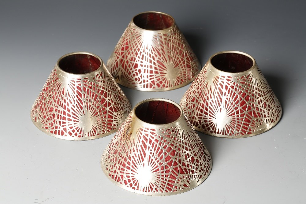 TIFFANY STUDIOS: A SET OF FOUR CANDLE SHADES with pierc: TIFFANY STUDIOS: A SET OF FOUR CANDLE SHADES with pierced 'spider's web' designs and red Mica type backing, stamped 'Tiffany Studios' and 'Pat Apld. 4', 5" wide (4)