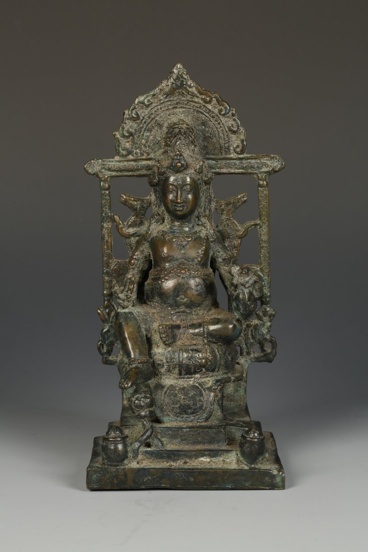 AN INDONESIAN BRONZE KUBERA FIGURE, the deity seated on: AN INDONESIAN BRONZE KUBERA FIGURE, the deity seated on an elaborate throne with one leg raised, on a stepped platform base, 12th-14th century, 9.5" high. Sold with an Oxford Labs Certificate. Sample: