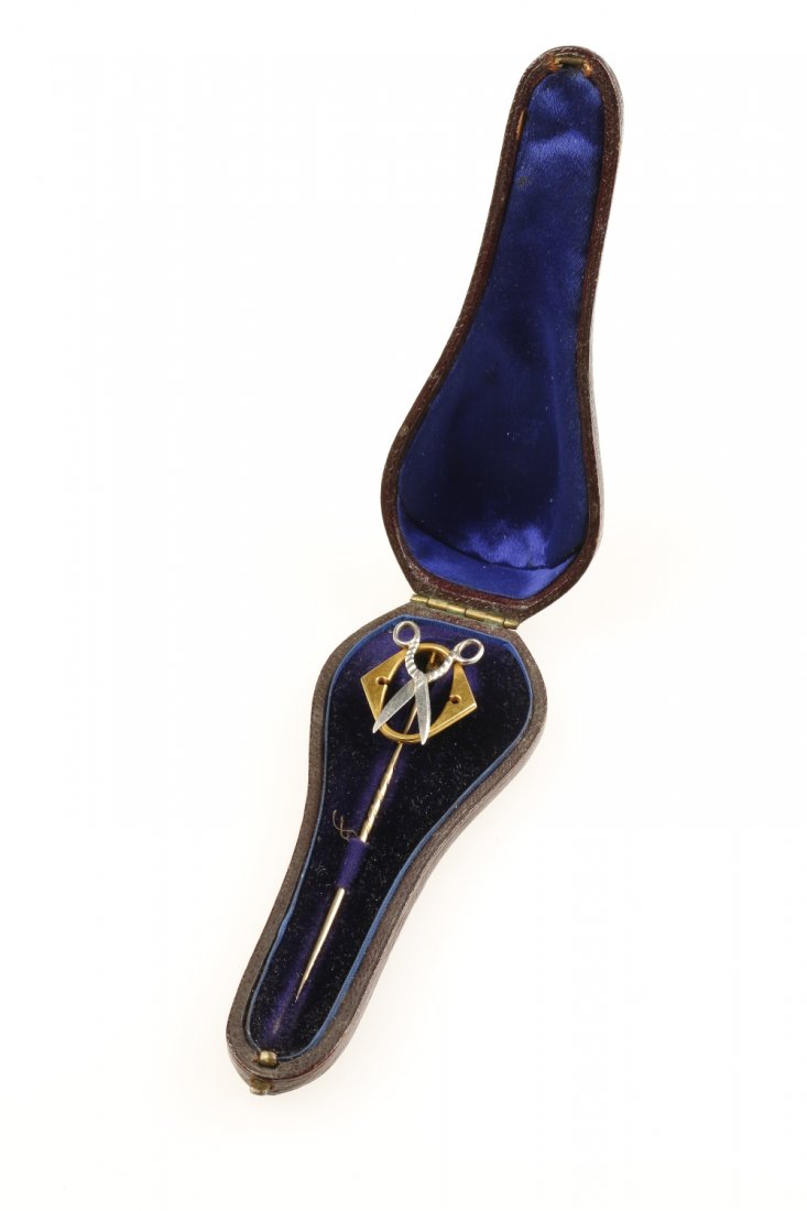 ROYAL INTEREST: A YELLOW AND WHITE METAL STICK PIN: ROYAL INTEREST: A YELLOW AND WHITE METAL STICK PIN modelled with a pair of open scissors and the letter "O", in a fitted case, bearing an old paper label "Given to me by HRH The Prince of Wales at San