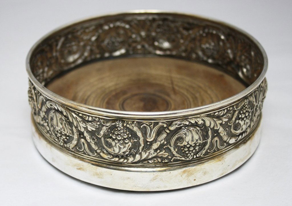 Tiffany Large Silver Champagne Coaster c. 1880: Large antique silverplated champagne sized bottle coaster chased with figural grape decoration and with a wooden base and green felt bottom, made by Tiffany & Co. in the United States c. 1880. Approxi