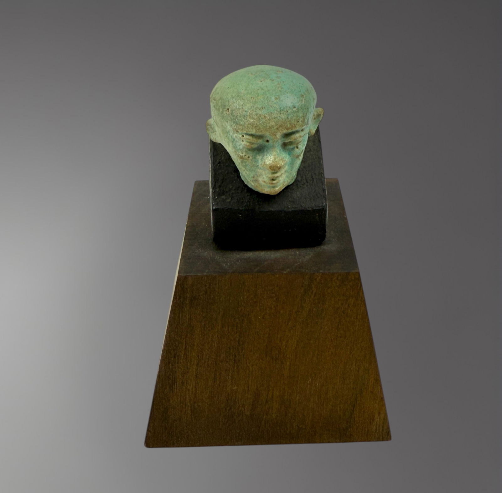 Egyptian Faience Head of Ptah – 1st Century BC: A rare faience head of the god Ptah, dating to the 1st century BC, during the Ptolemaic Period of ancient Egypt. Mold-formed in a vivid blue-green glaze, the head depicts the creator god Ptah wearing