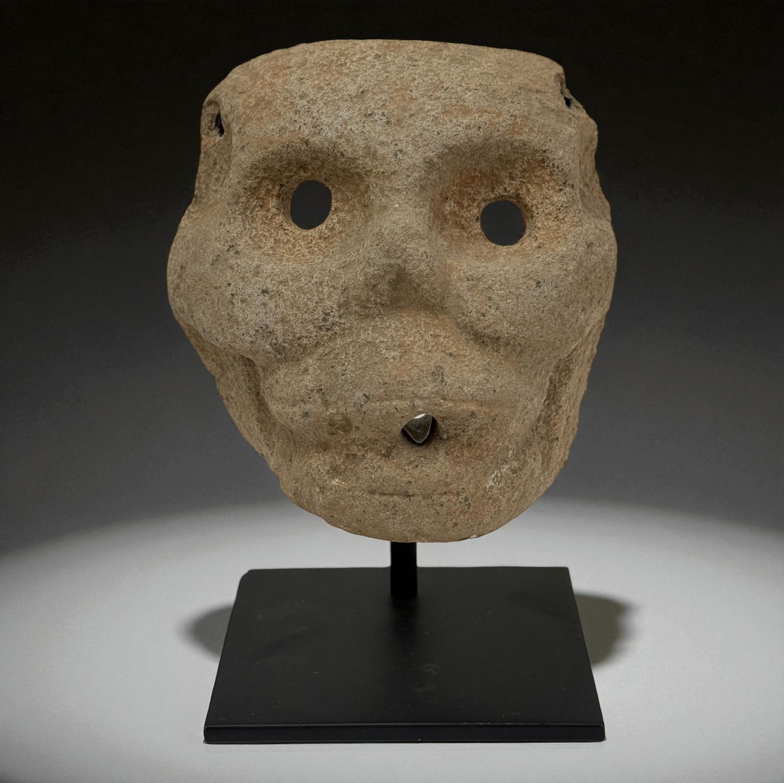 Pre Columbian Olmec Stone Mask with Nose Ornament: Carved stone ceremonial mask featuring drilled nose ornament and hollowed eyes; Provenance: Beverly Hills Barakat Gallery Collection.4 7/8" tall. 5" wide.