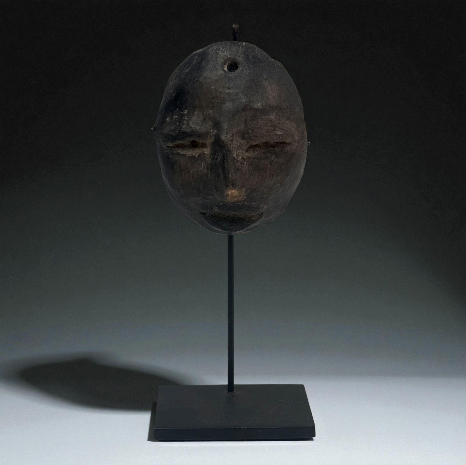 Pre-Columbian Wooden Ritual Mask: Carved wooden mask with recessed eyes and minimalist facial shaping, likely used in ceremonial contexts.Provenance: Beverly Hills Barakat Gallery Collection. 3" tall.