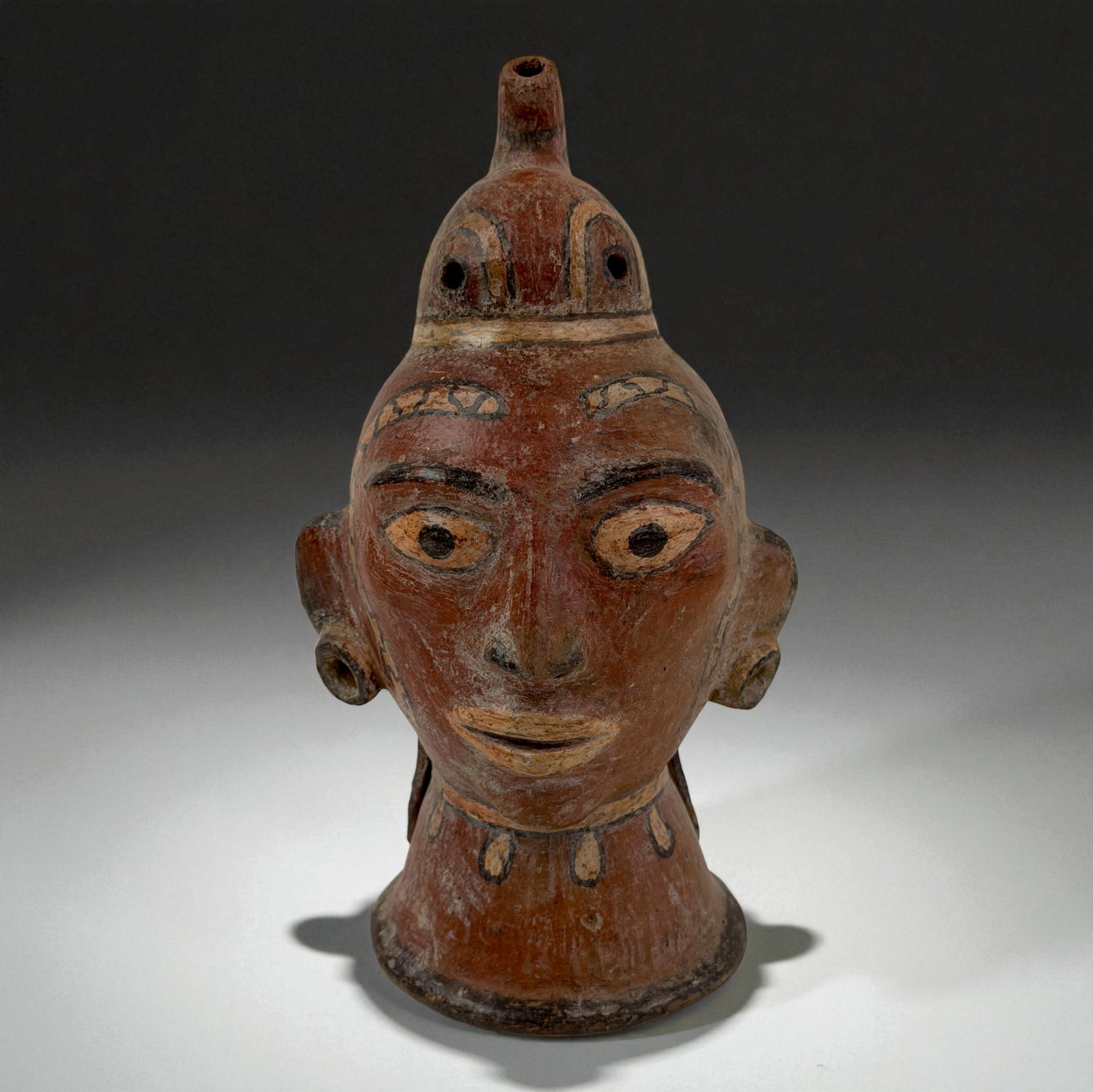 Pre-Columbian Terrcaotta Polychrome Head Vessel: Portrait head vessel with large eyes, painted features, and modeled crest top. Provenance: Beverly Hills Barakat Gallery Collection.