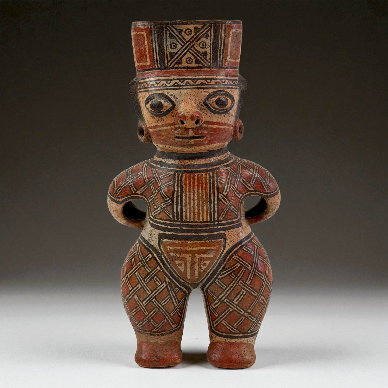 Pre-Columbian Standing Painted Figure: Terracotta standing figure with detailed red and black painted geometric patterns across the body and tall headdress. Expressive eyes, strong stance, and carved openings at the arms enhance its ritual