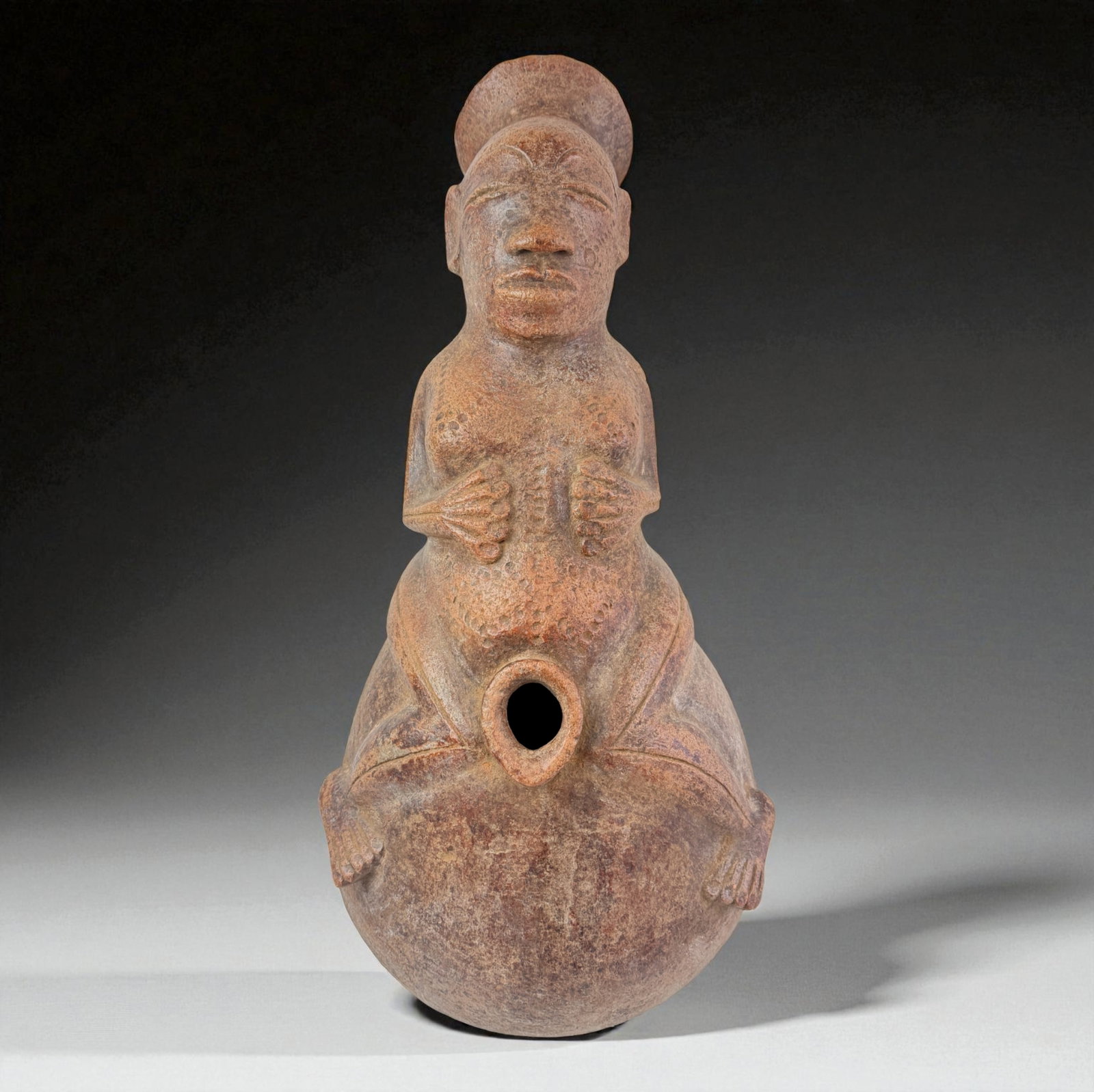 Pre-Columbian Gourd-Form Effigy Vessel: Gourd-form effigy with seated upper figure, central opening, and textured surface. Hands positioned over abdomen with strong symbolic representation. Provenance: Beverly Hills Barakat Gallery Collecti